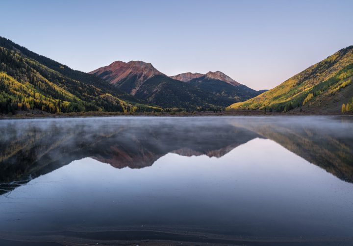 Serene Mountain Lake Surrounded by Lush Forest and Vibrant Autumn Foliage